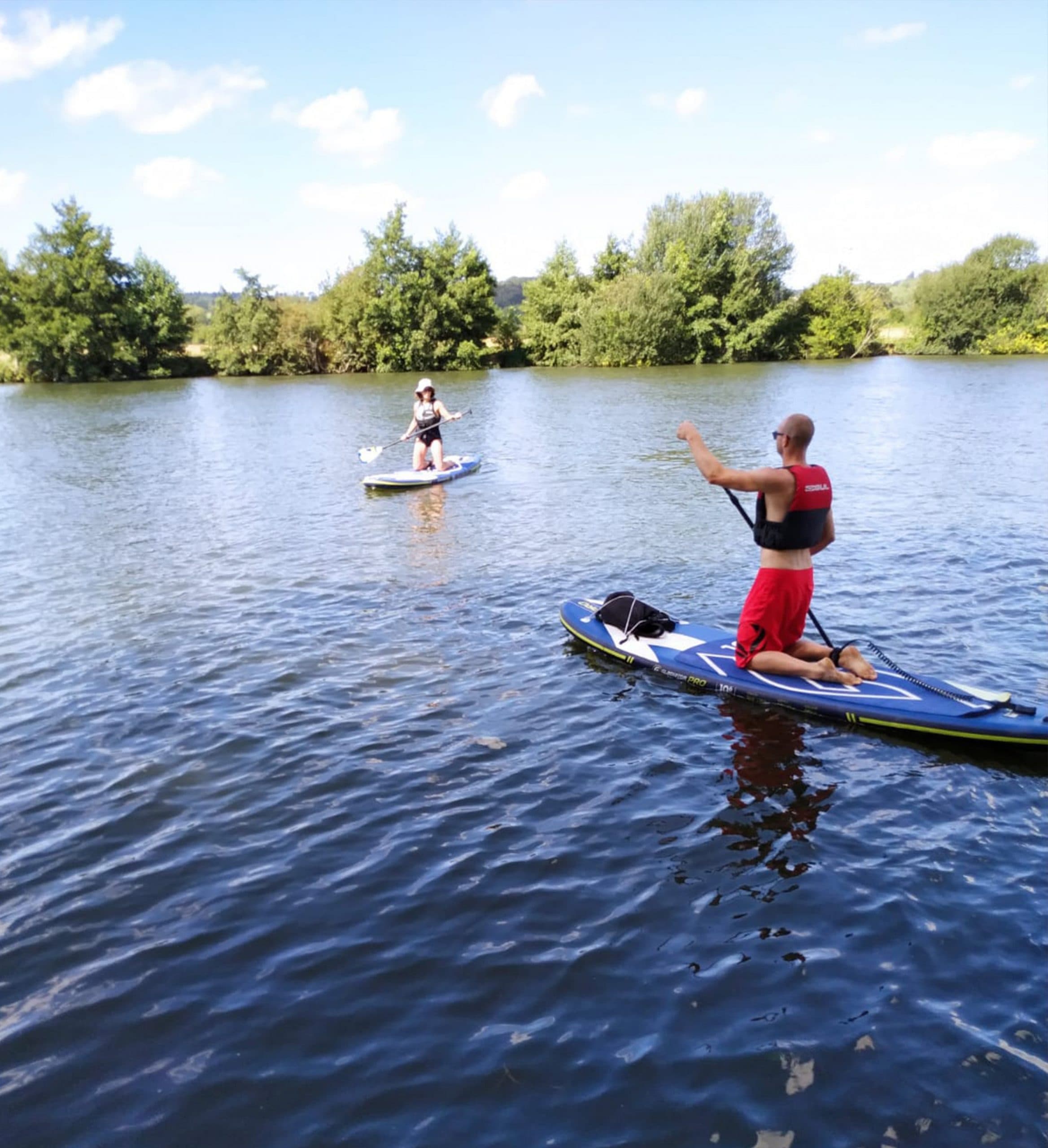 Standup paddleboarders practicing on wide river under blue sky