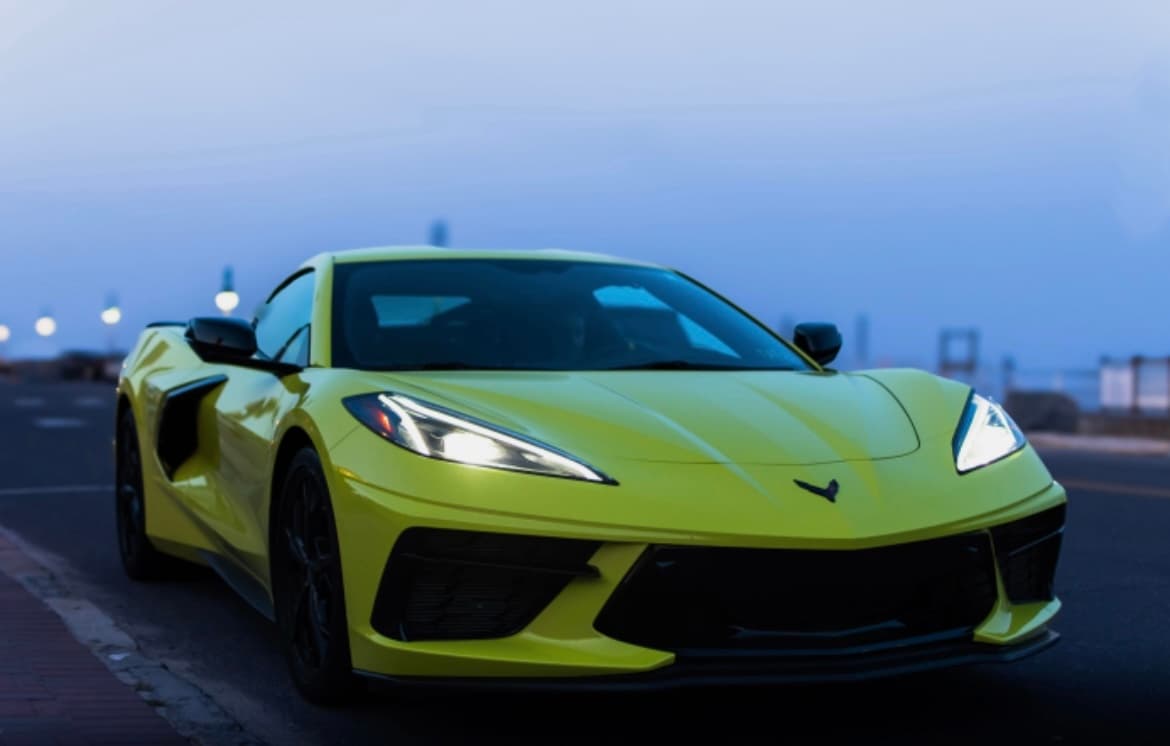 Yellow sports car on coastal road at dusk, seaside drive