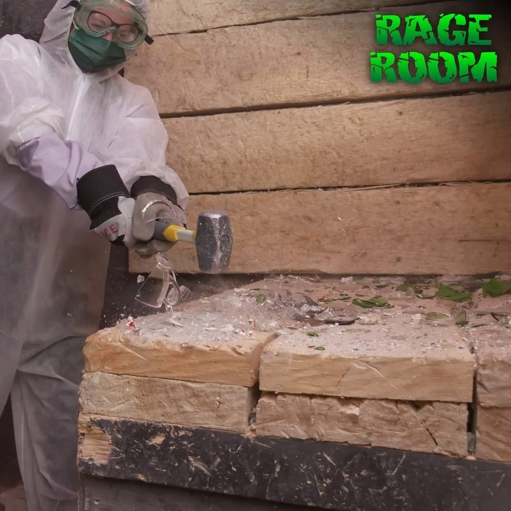 Participant smashing blocks in indoor rage room with safety gear