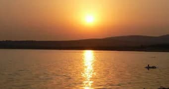Kayaker paddling at sunset on calm Austin lake shoreline