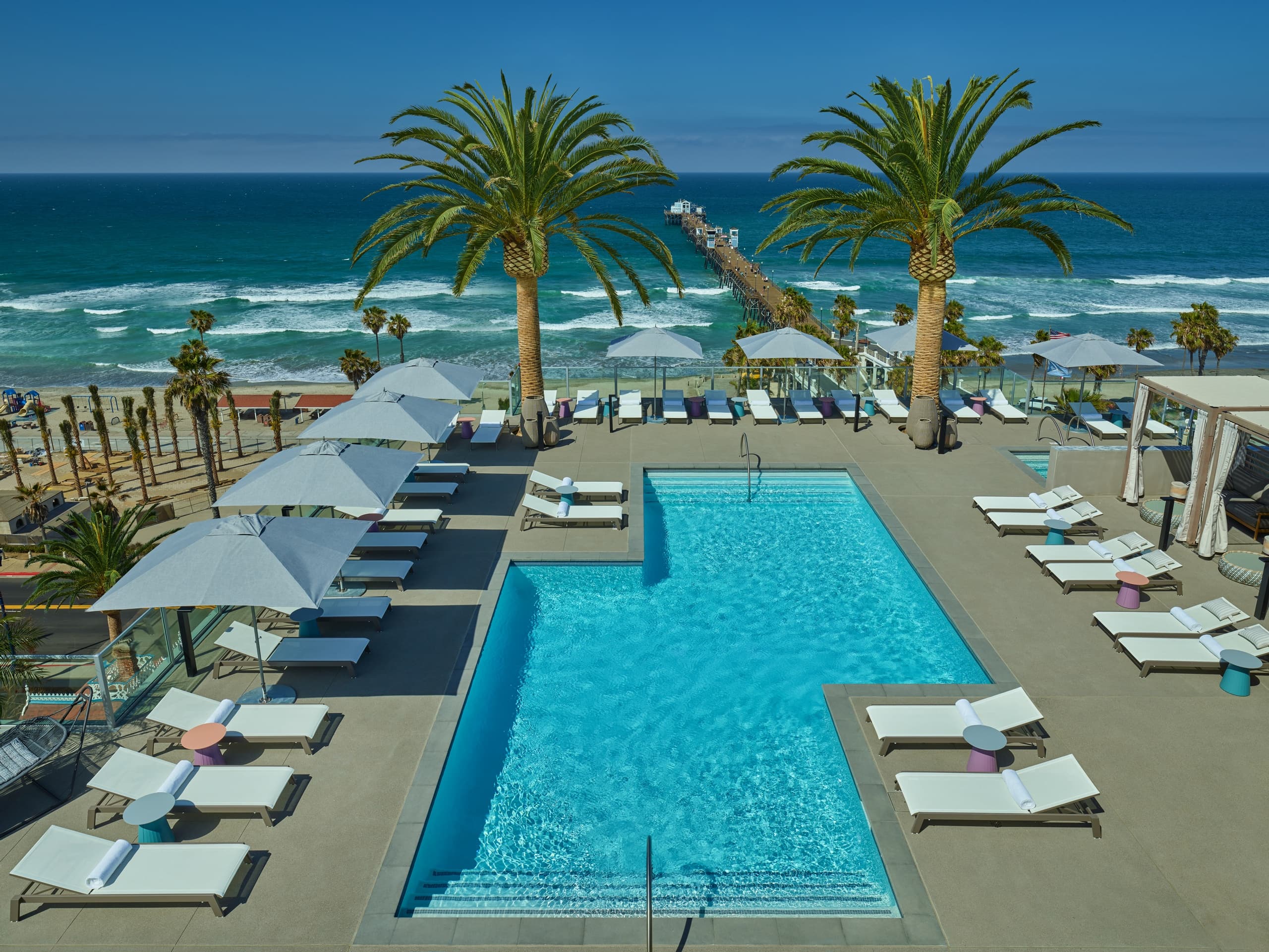 Aerial oceanfront resort pool with palm trees and cabanas