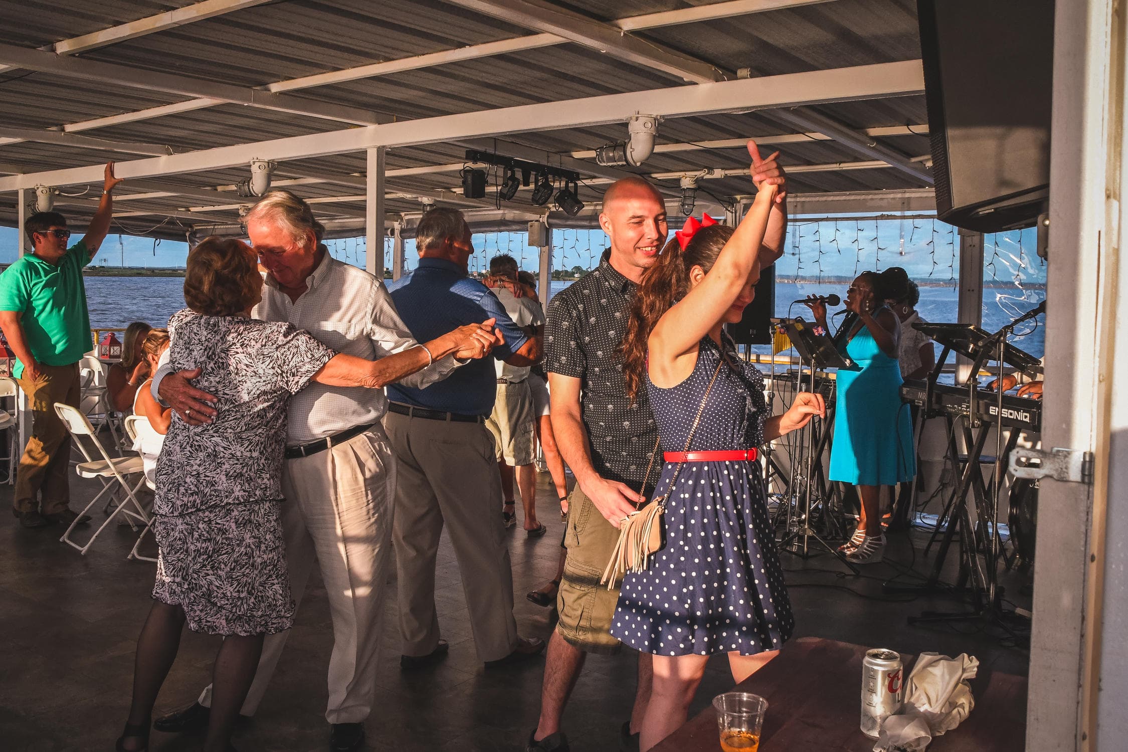 Couple and guests dancing on boat deck during sunset cruise