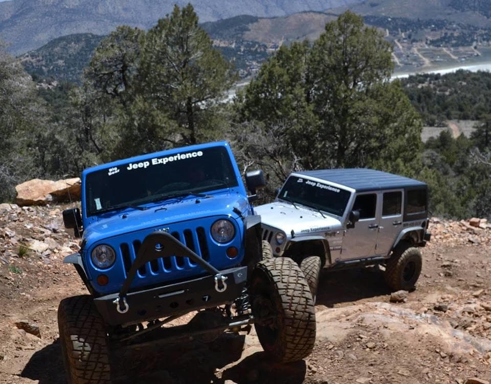 Blue Jeep leading off-road trail with mountain vista backdrop