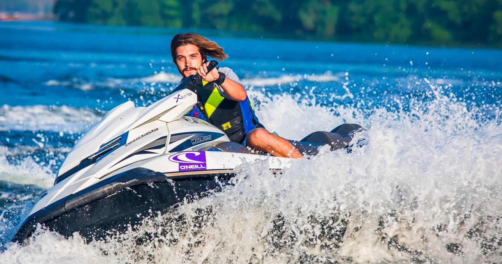 Rider jet skiing on a choppy lake creating big spray near shore