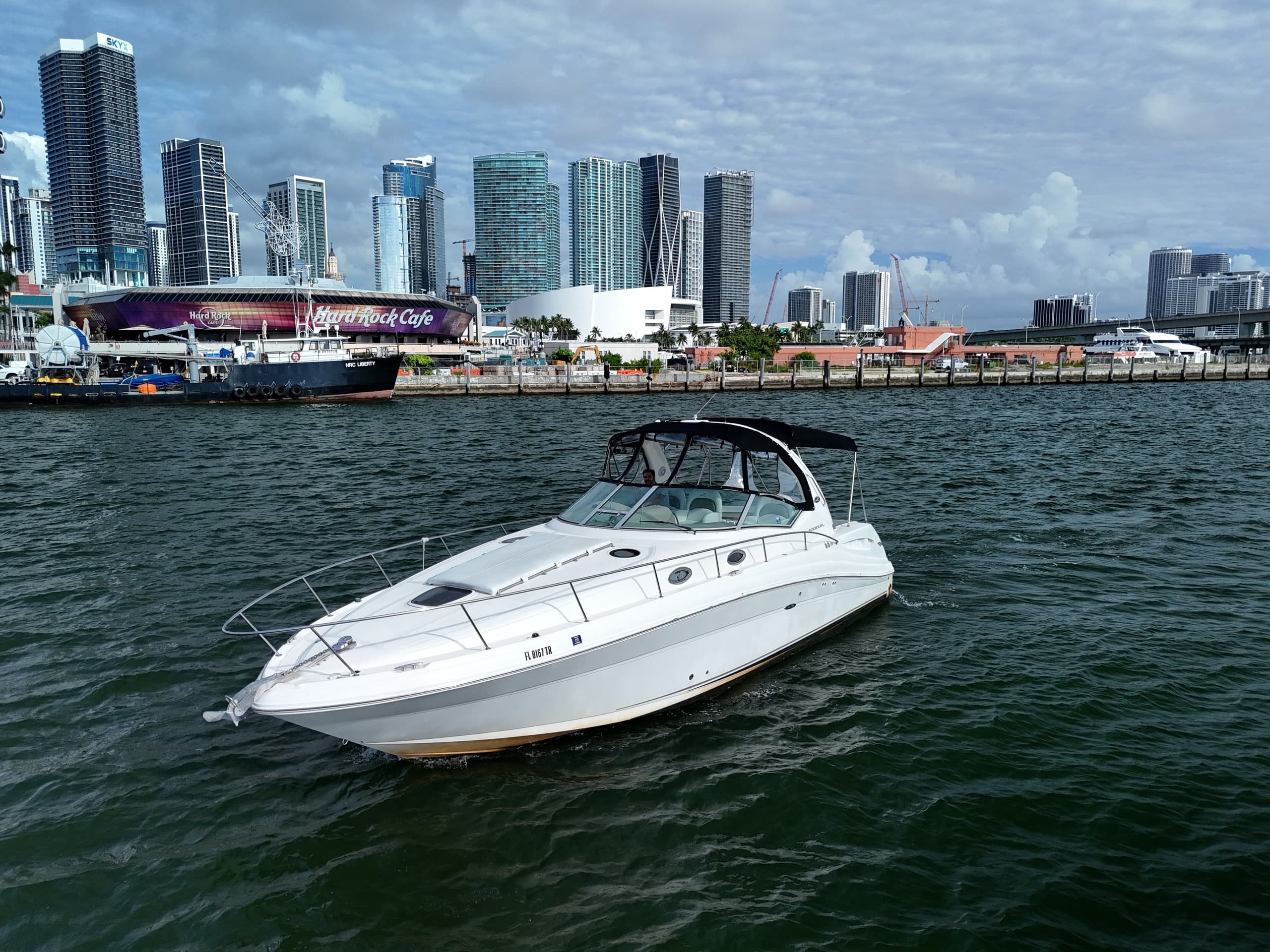 Luxury boat cruising harbor with waterfront city skyline behind