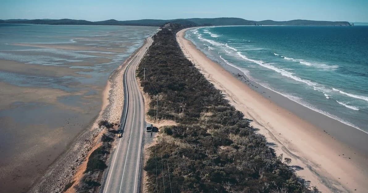Aerial coastal drive along narrow peninsula and sandy beaches
