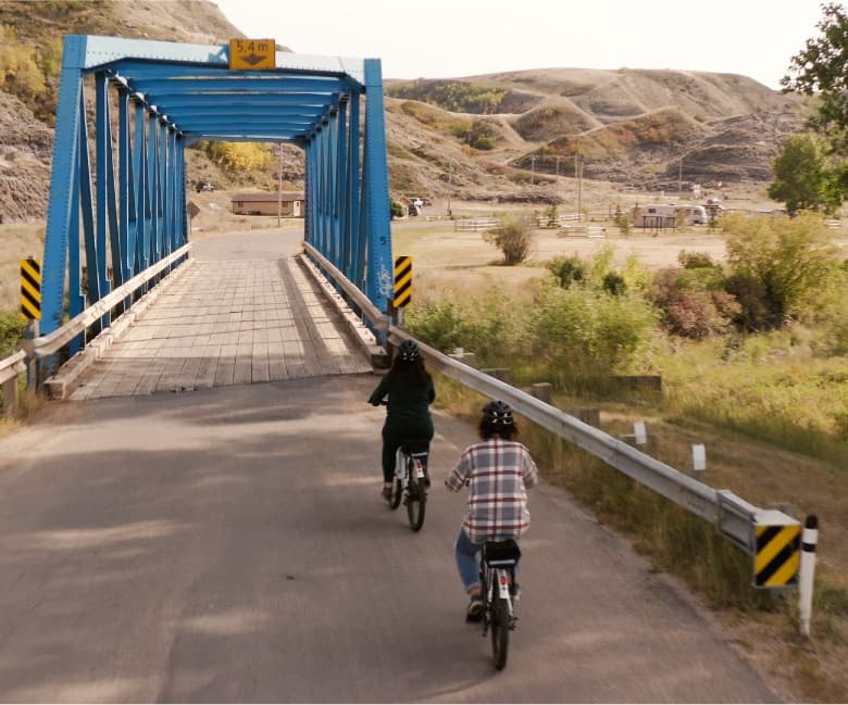 Cyclists crossing blue rural bridge on scenic paved country road