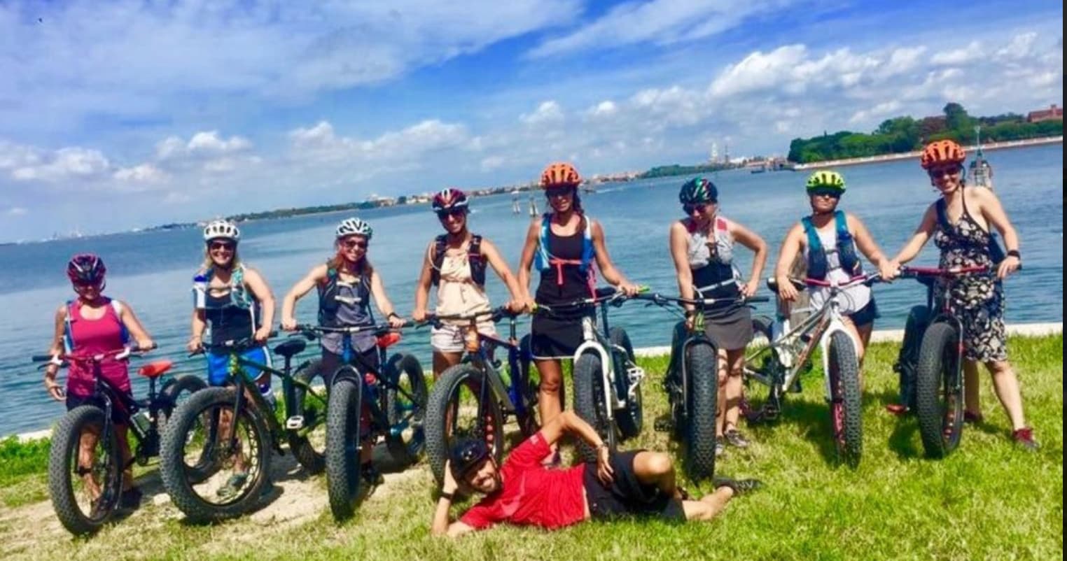 Group riding fat-tire e-bikes along lakeshore meadow