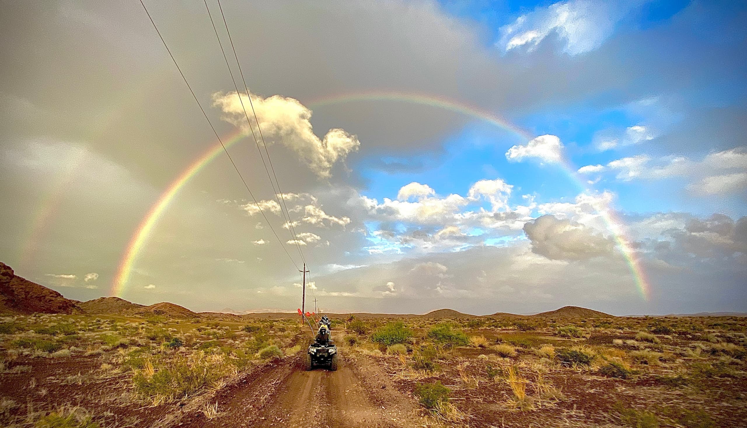 ATV riding on desert trail under a double rainbow in Nevada