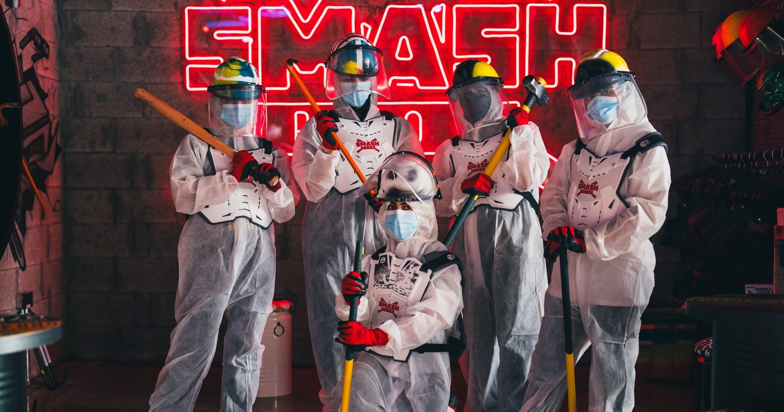 Team in protective suits posing in Abu Dhabi indoor smash room