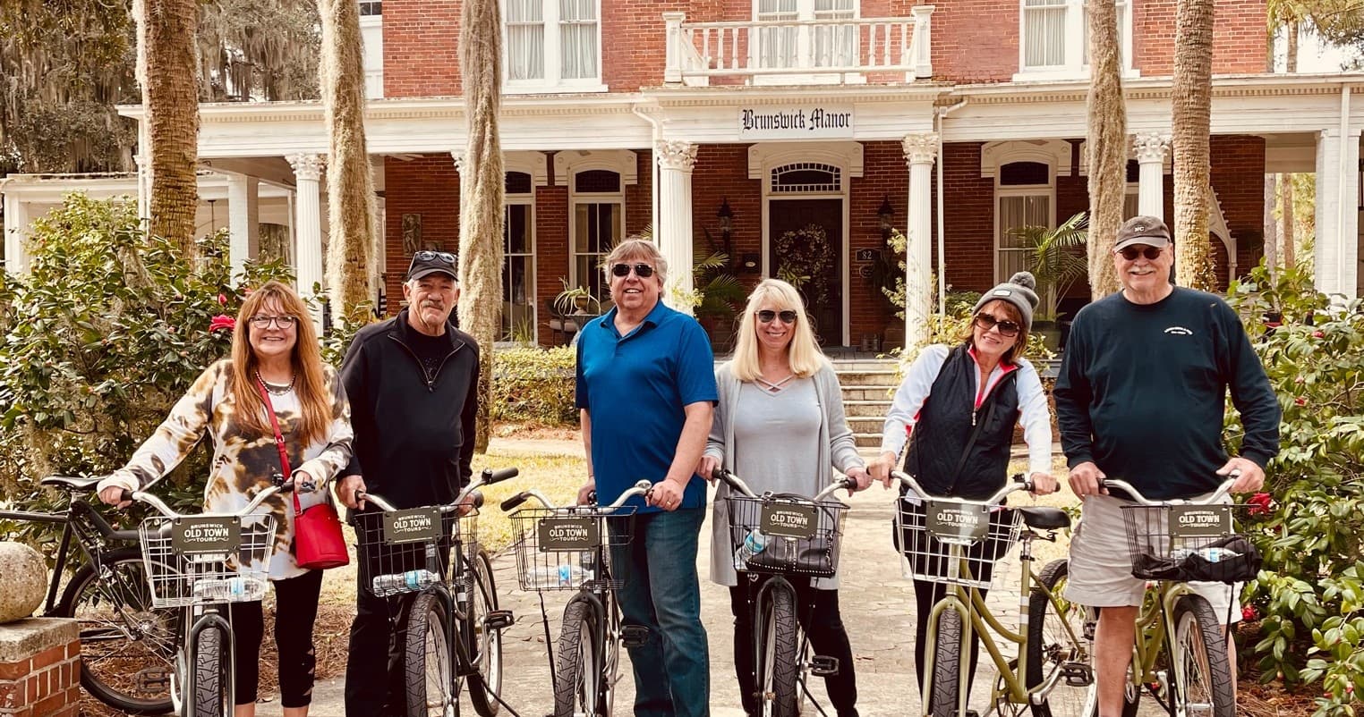 Small group on bike tour posing outside historic inn in Brunswick
