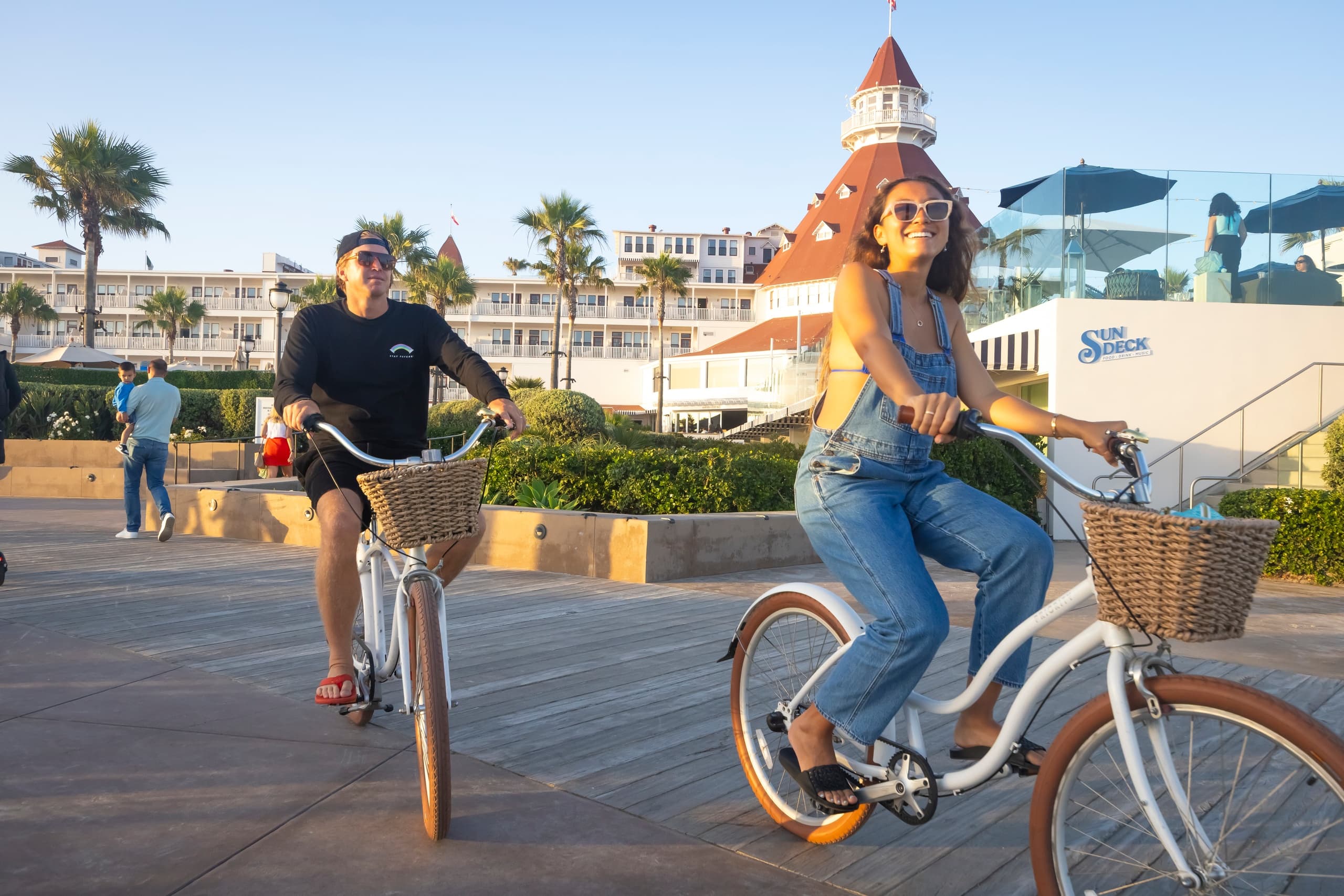 Cyclist cruising boardwalk with ocean view and palm trees, coastal