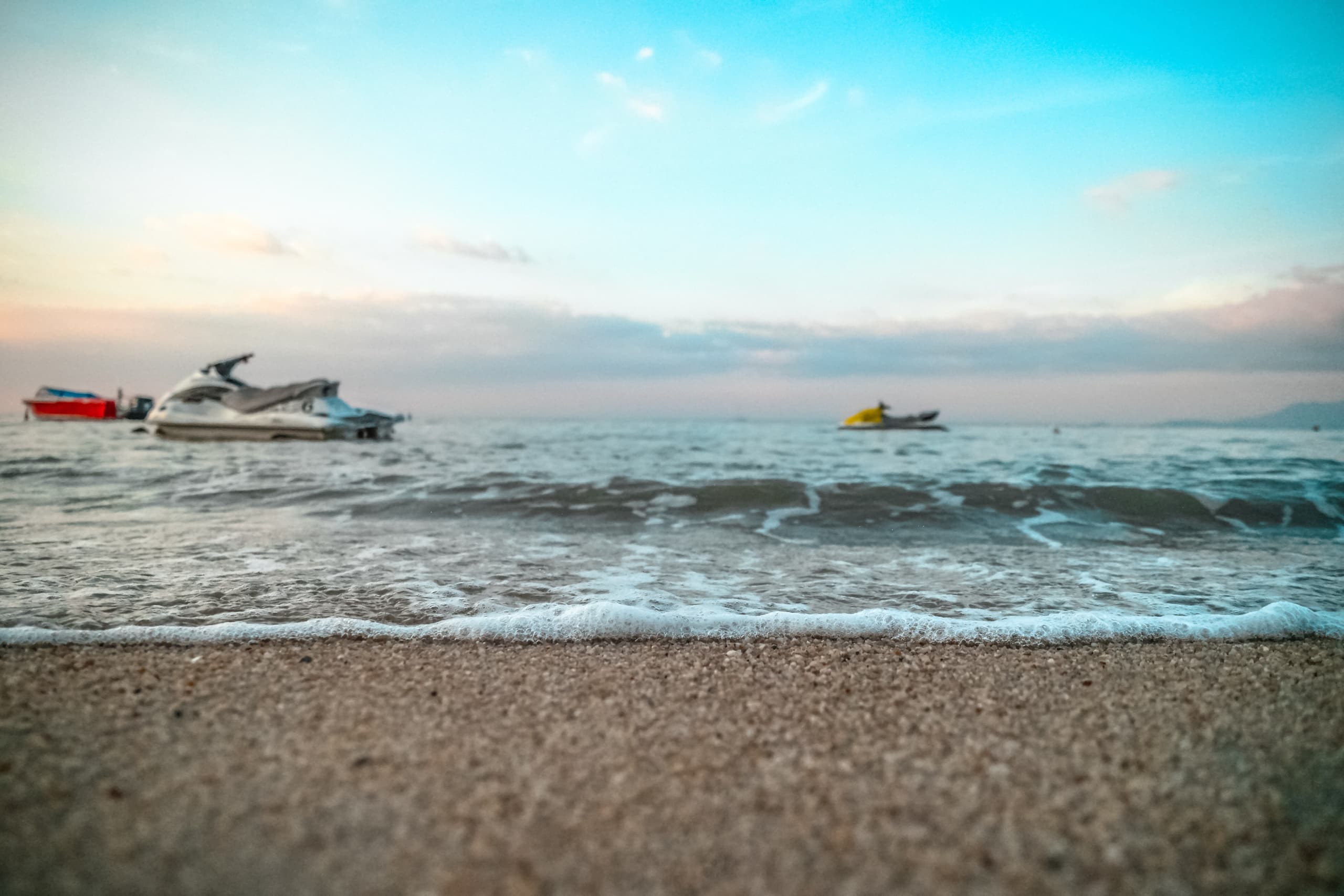 Sandy beach foreground with anchored boats on tranquil coastal horizon