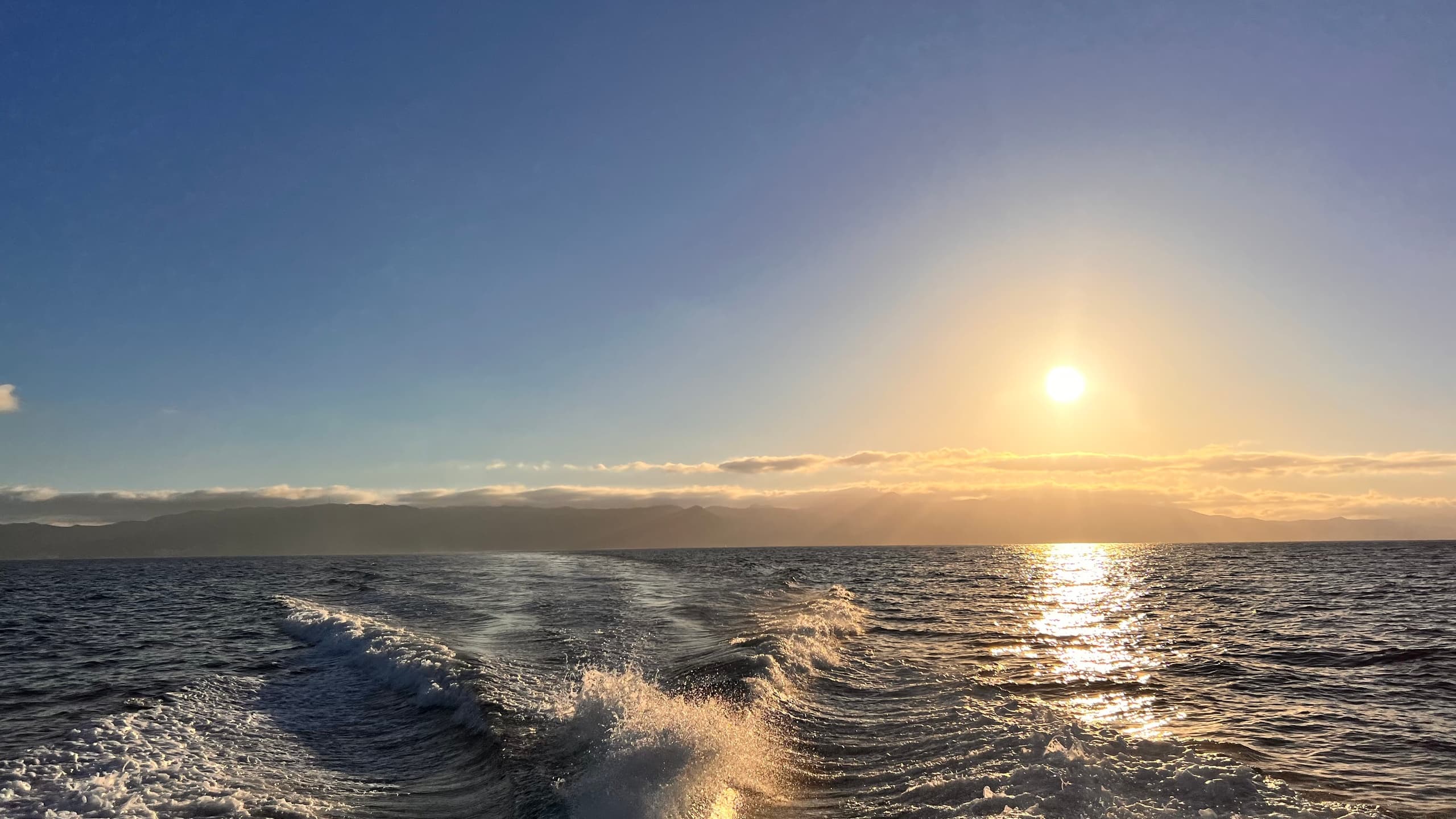 Motorboat cruising at sunrise on open ocean, frothy wake