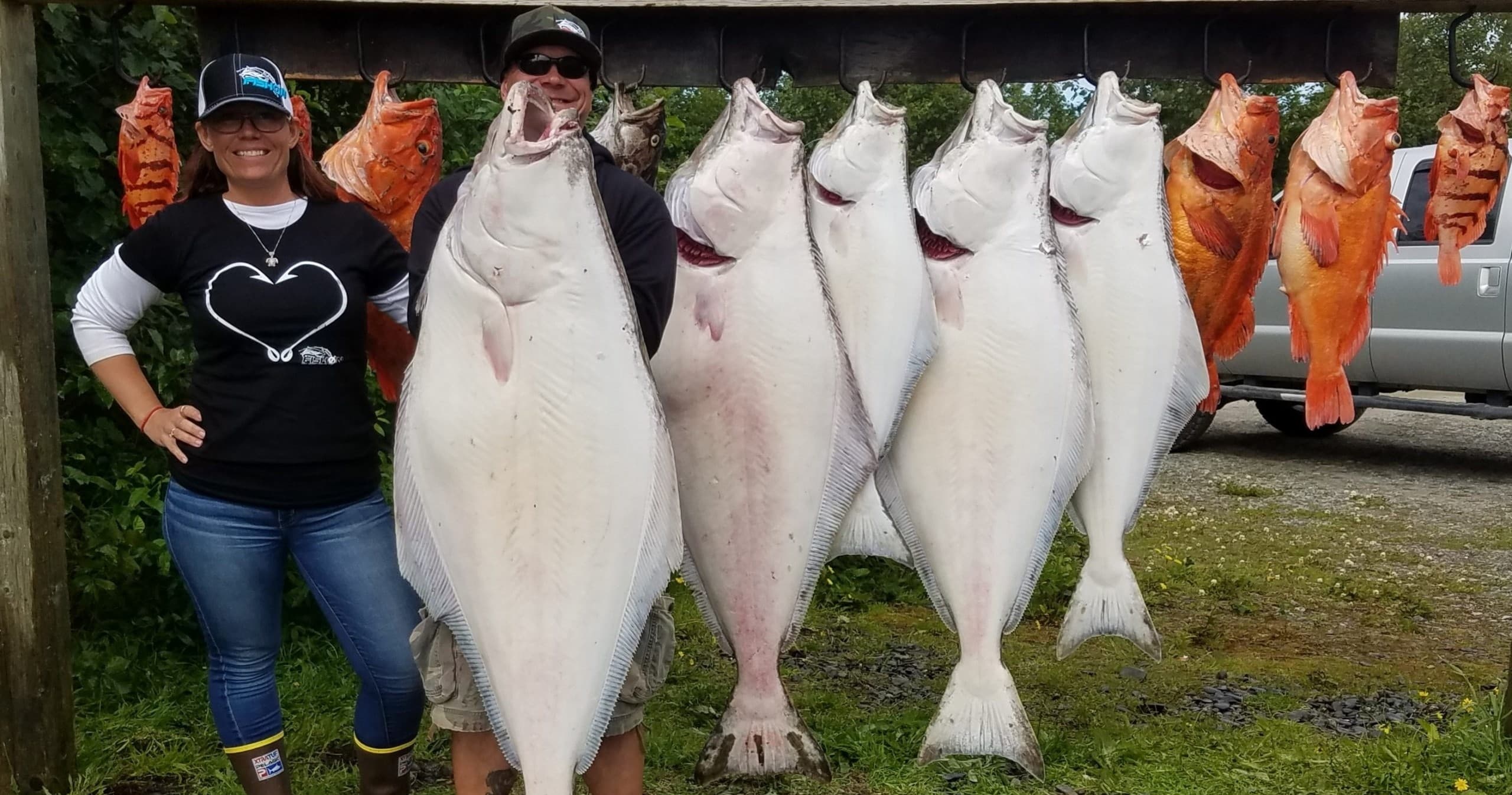 Anglers with hung halibut and rockfish beside Alaskan shore
