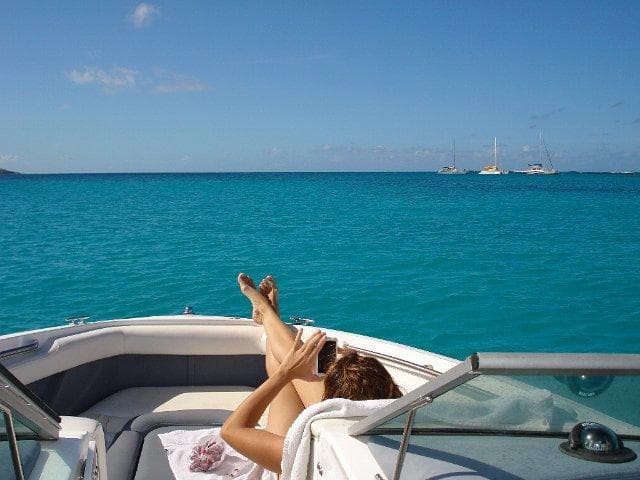 Sunbather on boat bow with clear ocean view, tropical day cruise