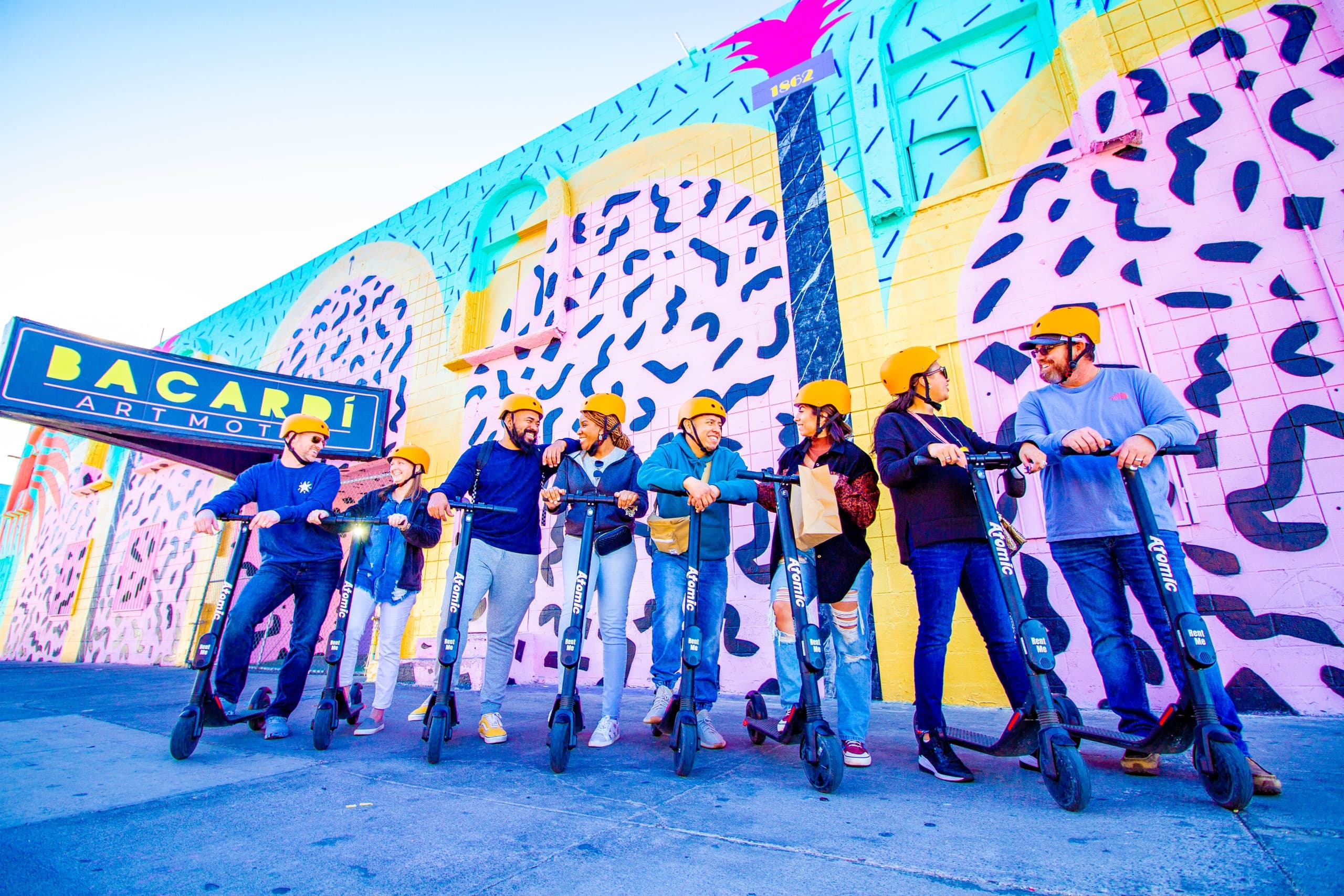 Guided scooter tour group lined up before colorful mural in Vegas