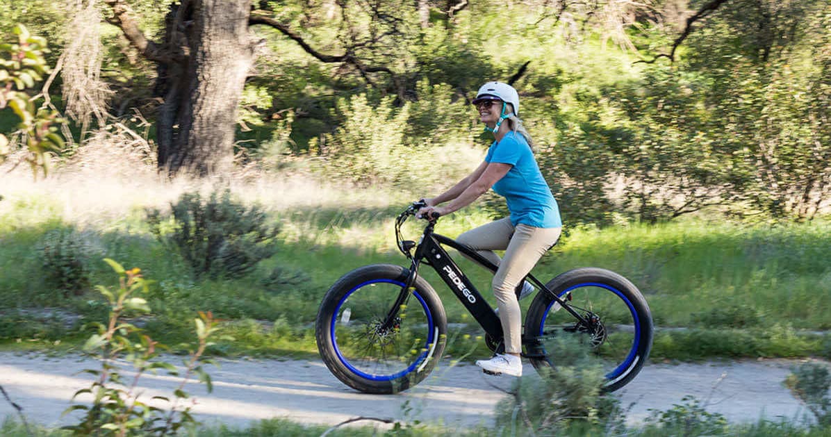 Person riding electric bike on forest trail during sunny day