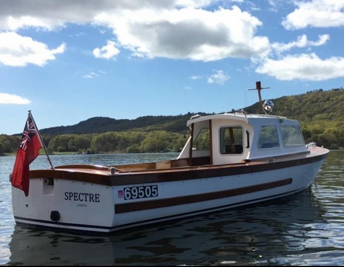Small motorboat 'Spectre' cruising on open lake with blue sky