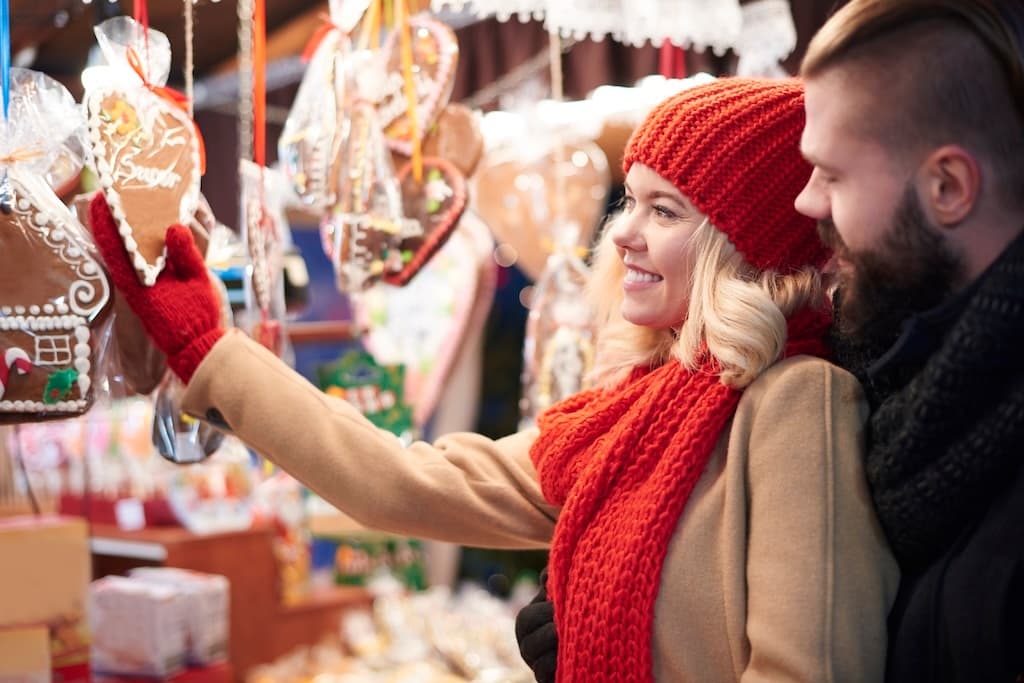 Couple browsing festive outdoor market stalls at winter fair