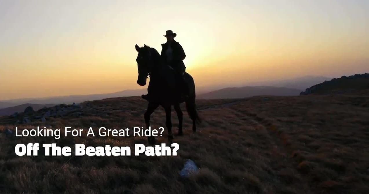 Silhouetted horseback rider at sunset on open ridge