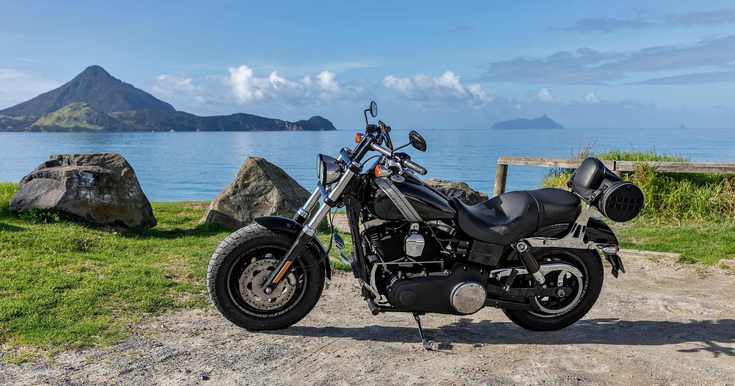 Black motorcycle parked by coastal bay with volcanic island views