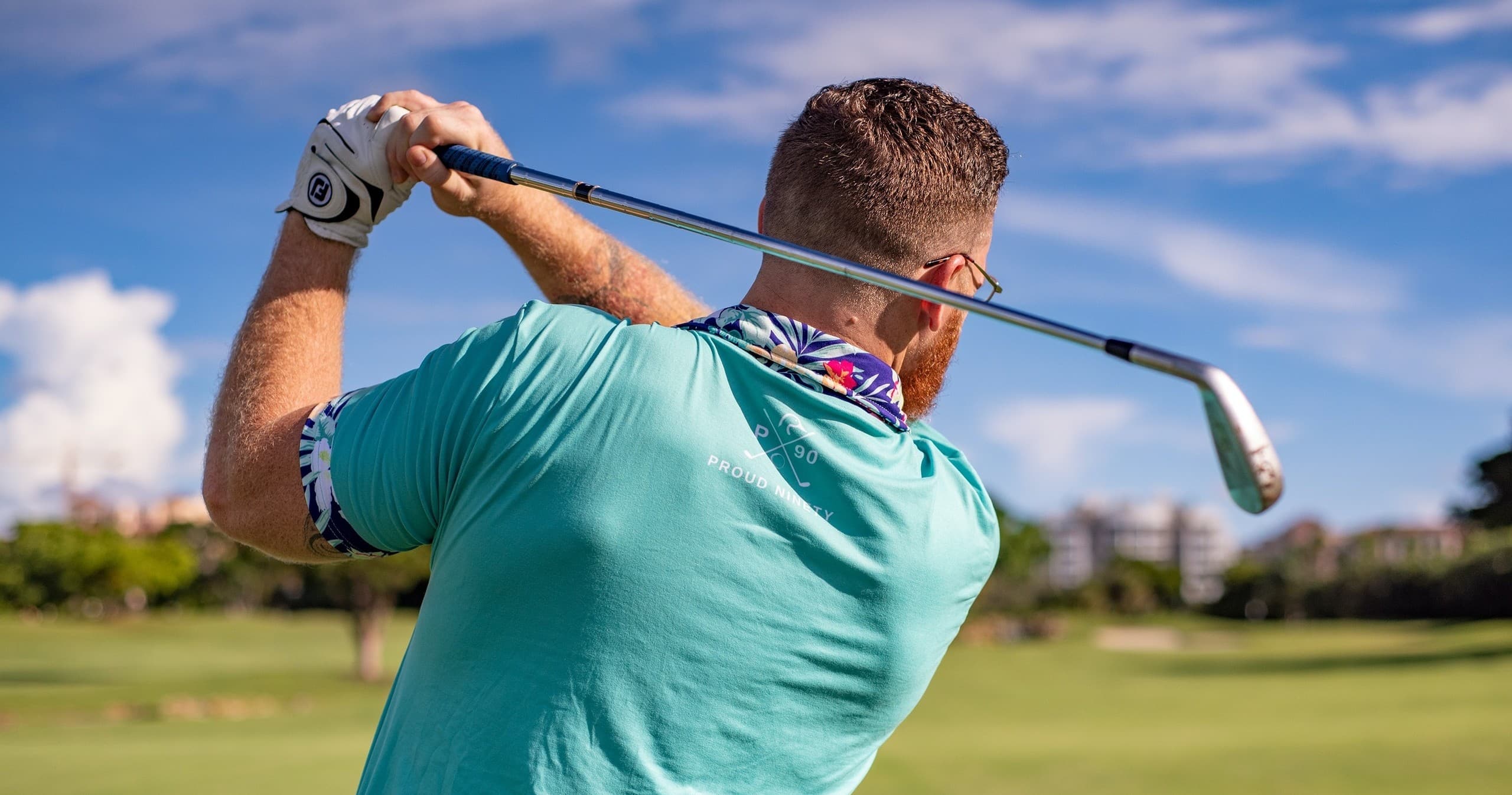 Golfer swinging iron on sunny fairway at coastal golf course