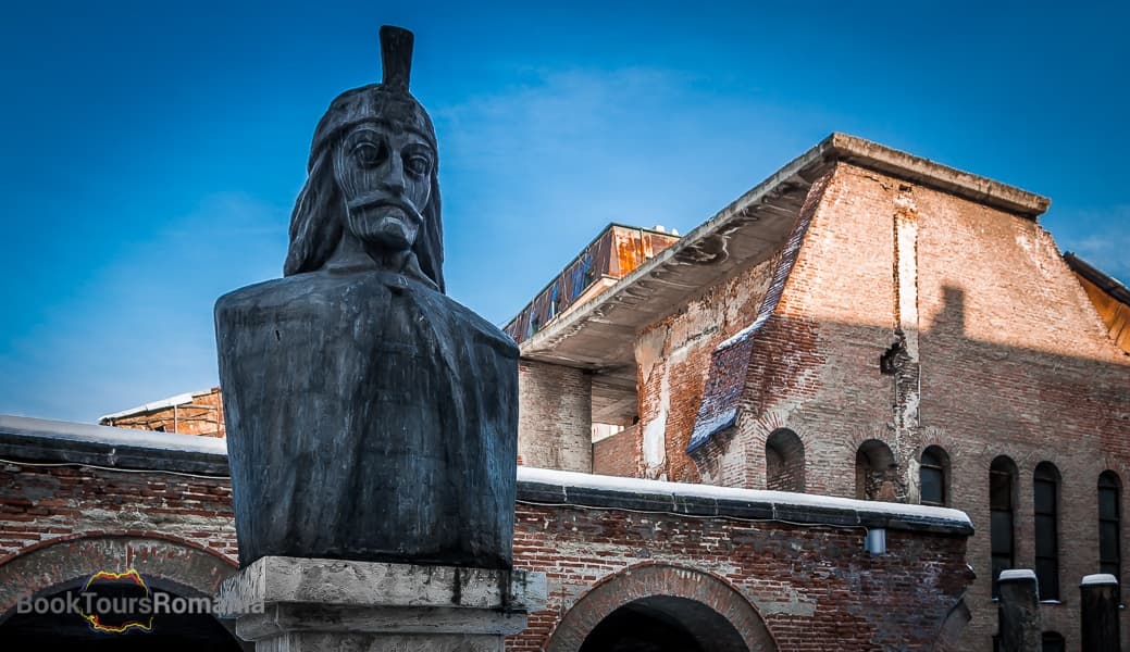 Historic statue and medieval ruins in Romanian citadel plaza