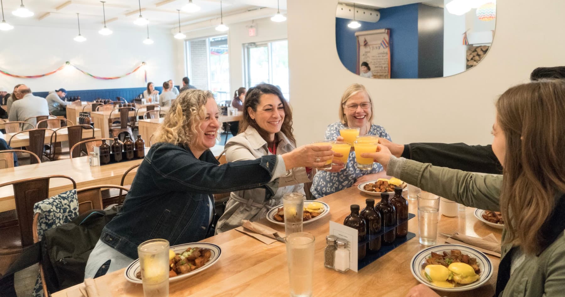 Friends toasting brunch at bright urban cafe during food tour