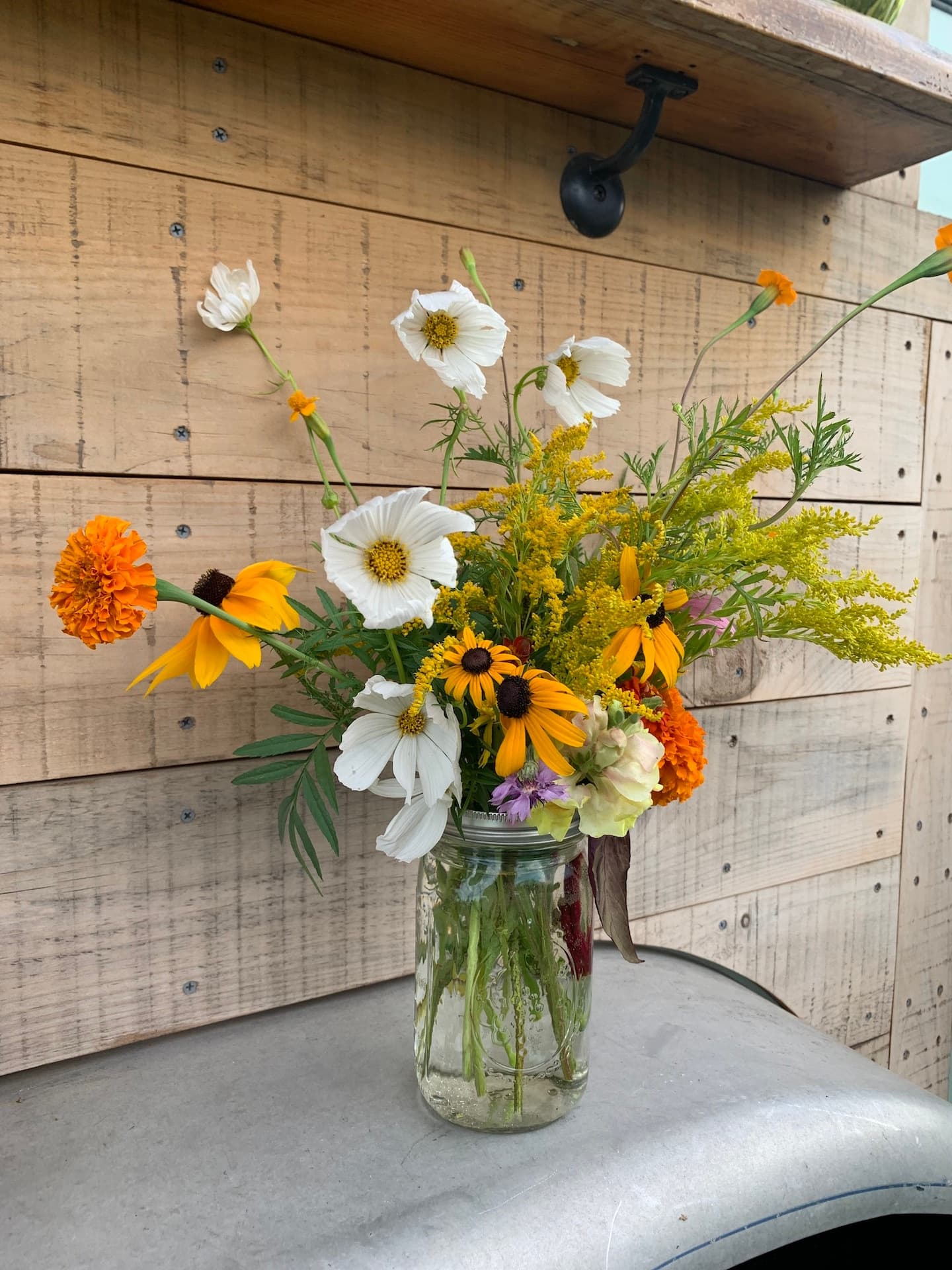 Mason jar wildflower bouquet displayed inside farm shop on counter
