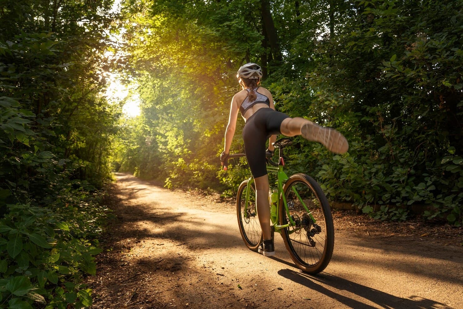 Mountain biker kicking up dust on sunlit forest trail