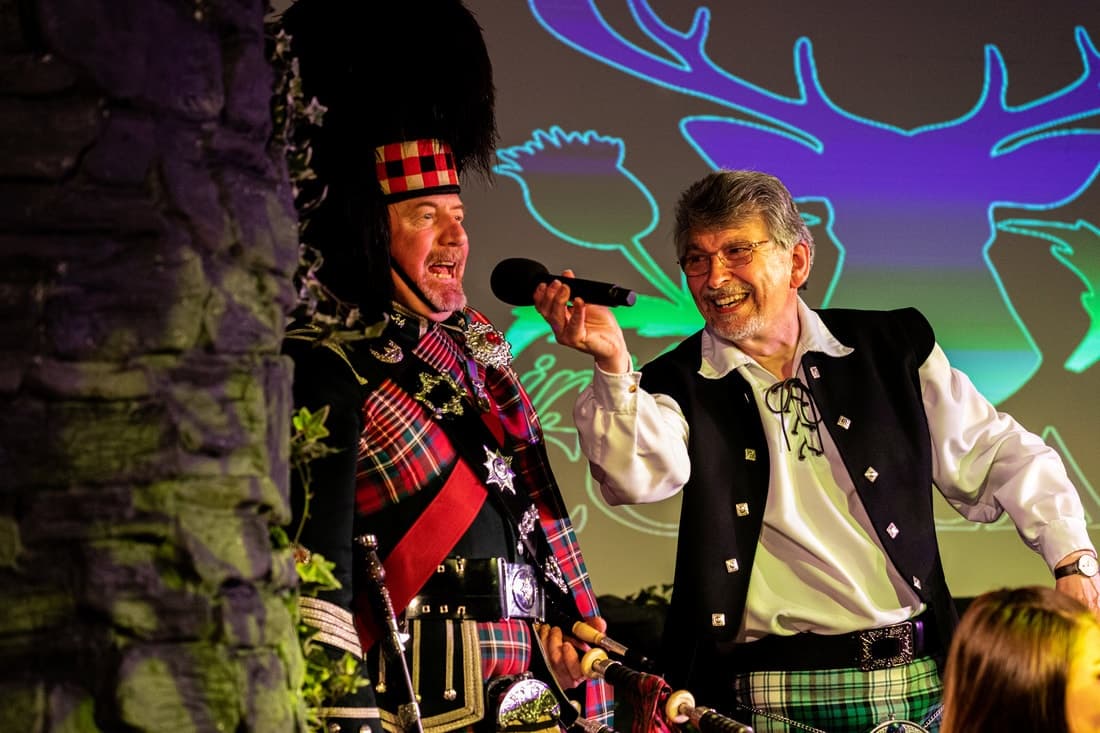 Scottish performers in tartan on indoor stage entertaining audience