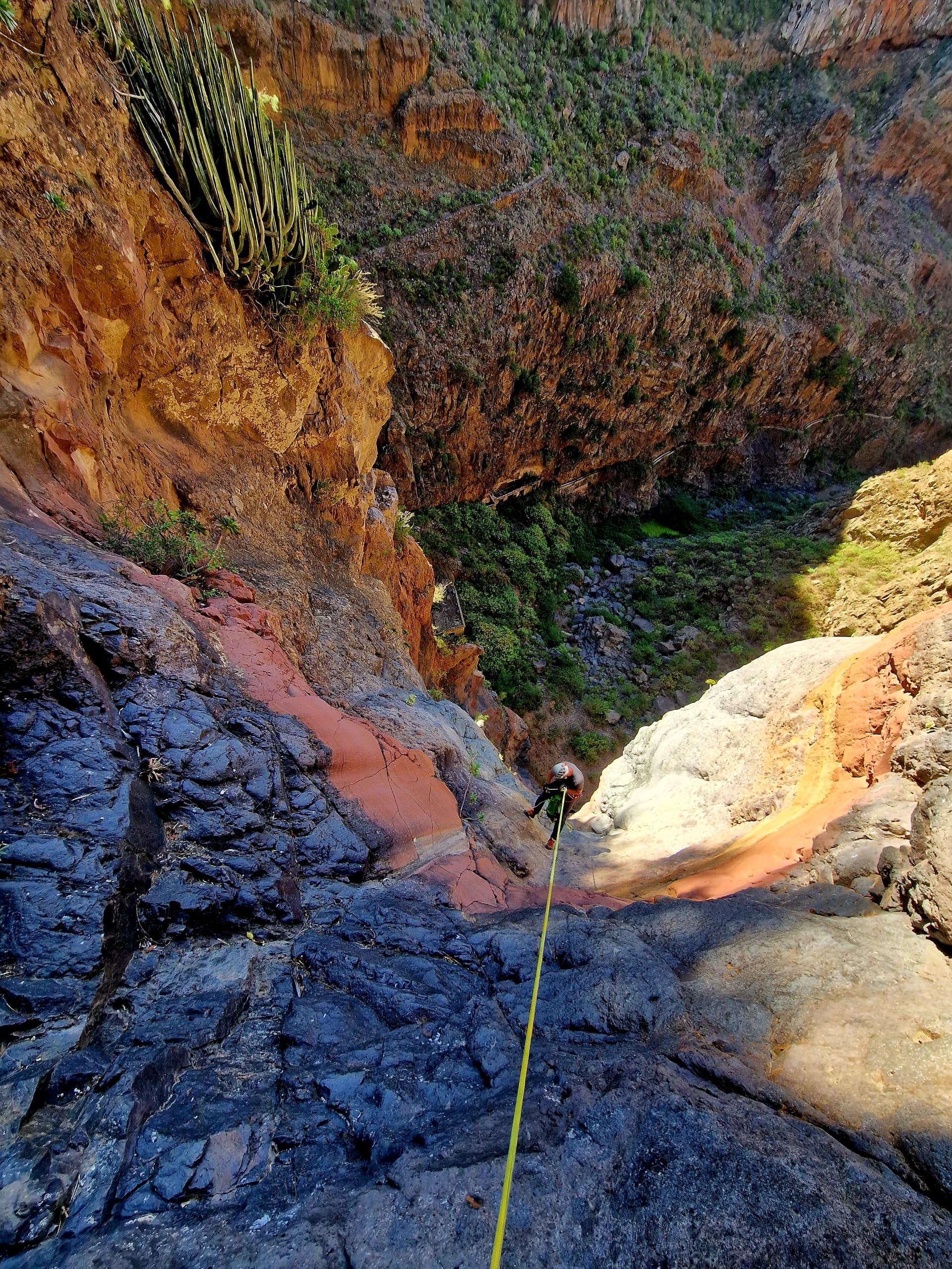 Rappeller descending colorful canyon wall with safety rope