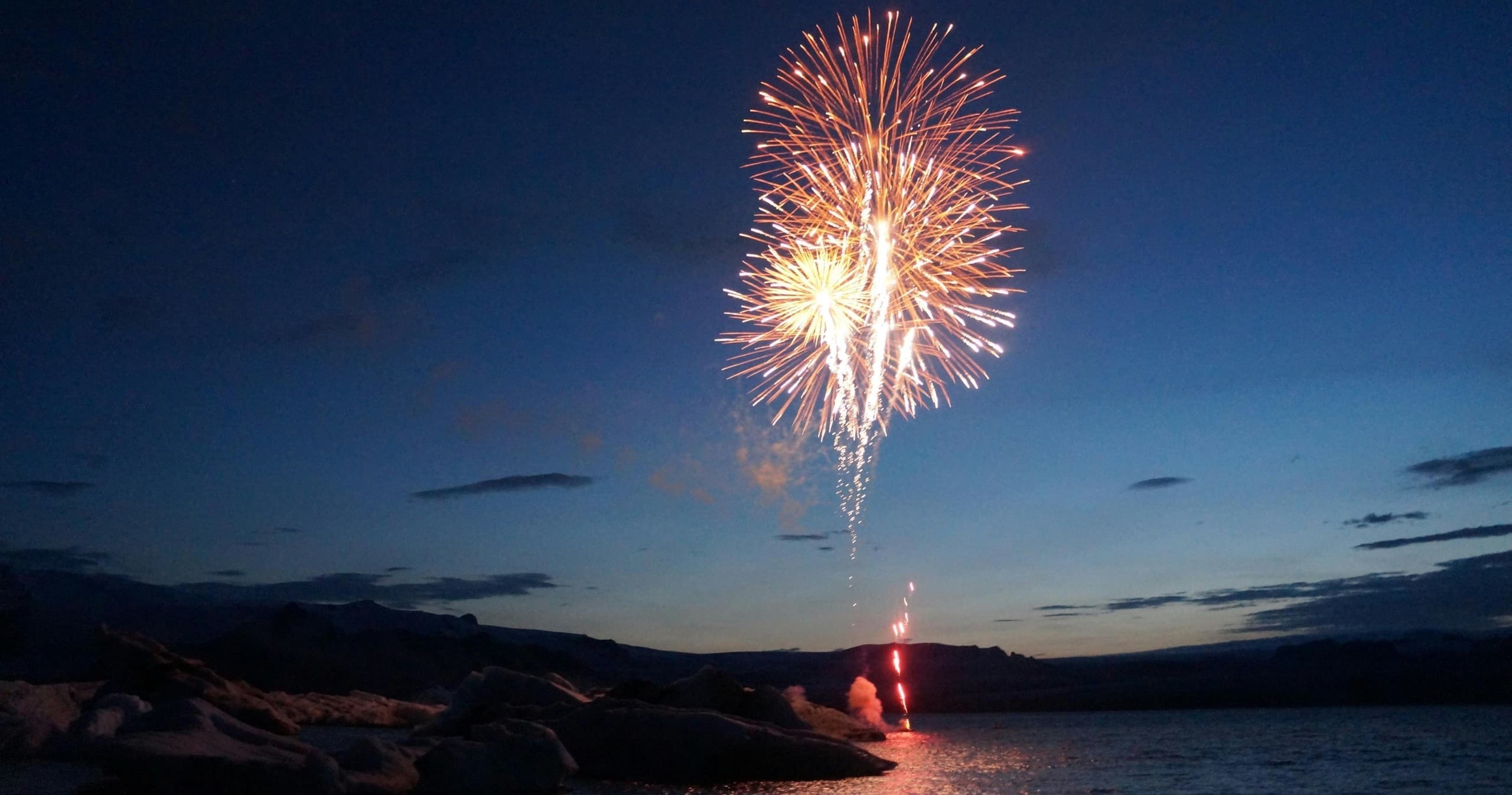 Fireworks display over coastal shoreline at dusk celebrating event