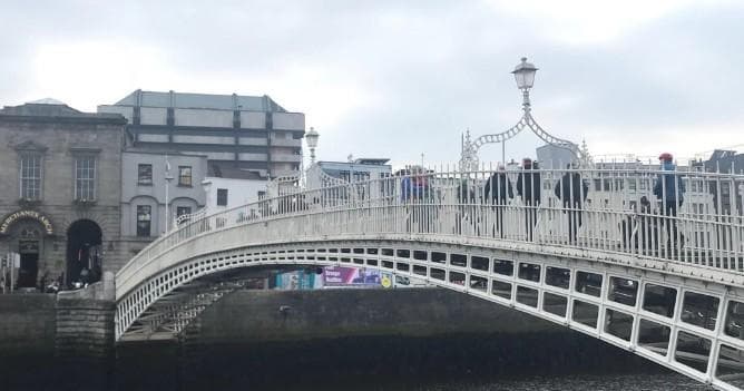 Walking tour crossing Ha'penny Bridge over River Liffey, Dublin