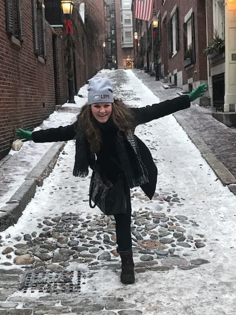 Woman posing on snowy Beacon Hill cobblestone during walking tour