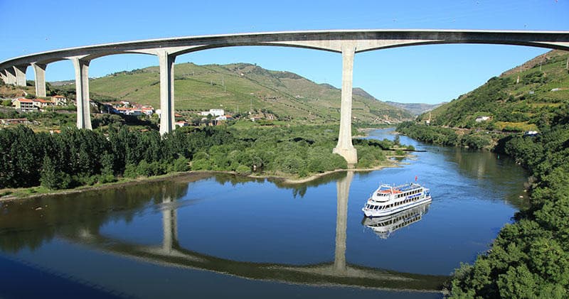 River cruise passing under concrete bridge in Douro Valley