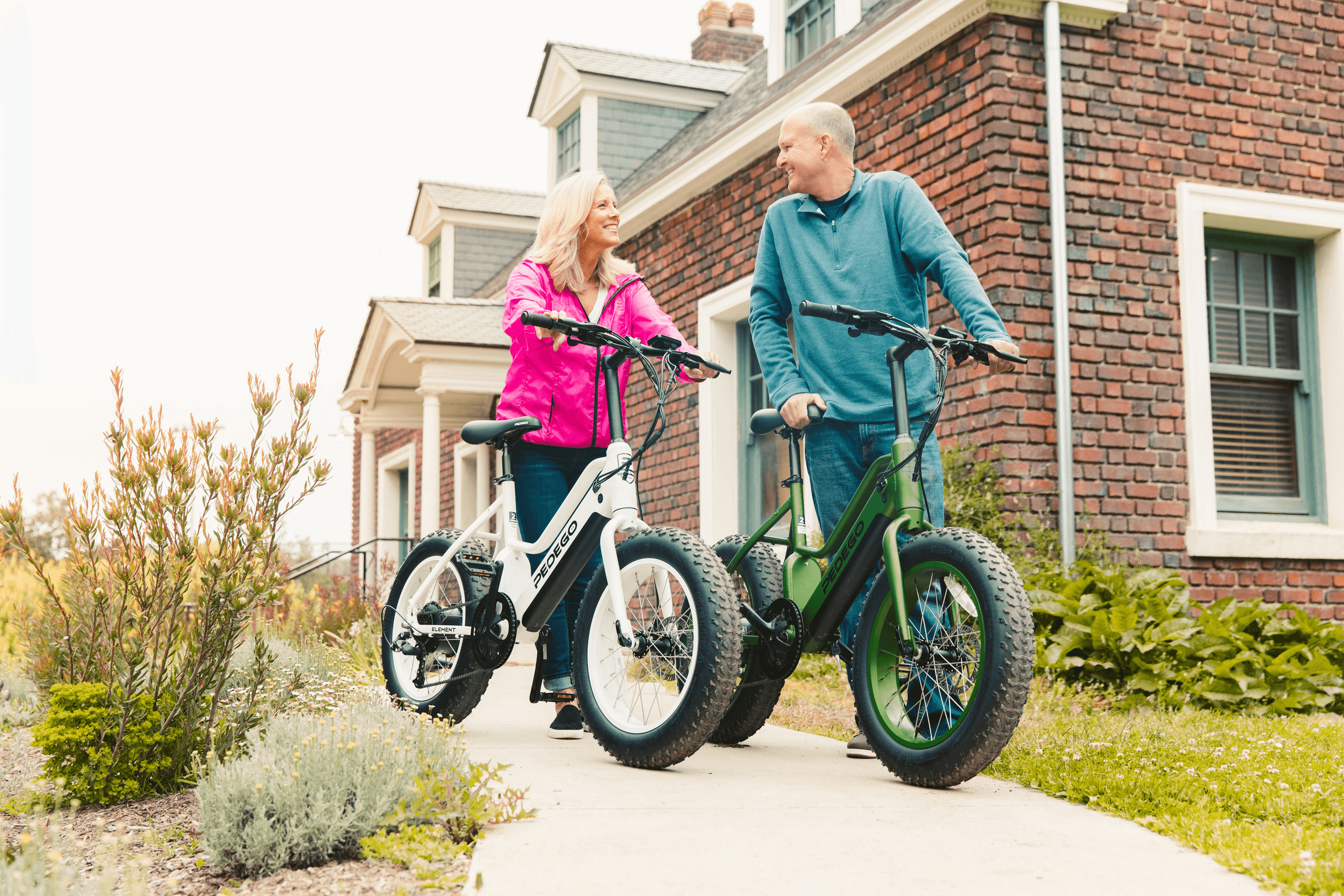 Couple with fat-tire e-bikes paused by a brick cottage walkway