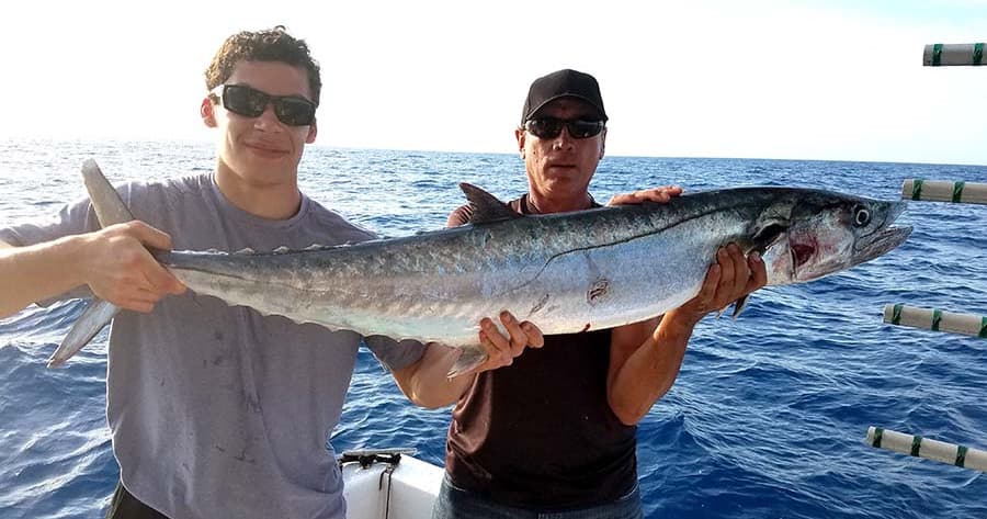 Two anglers holding a large barracuda on deep sea fishing trip