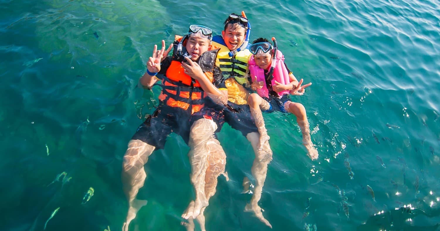 Family snorkeling and floating in clear turquoise ocean water