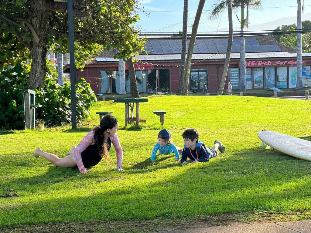 Family practicing surf stretches on grassy beachfront park