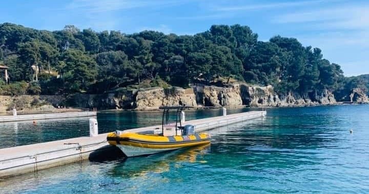 Small motorboat moored at rocky pier amid clear Mediterranean water
