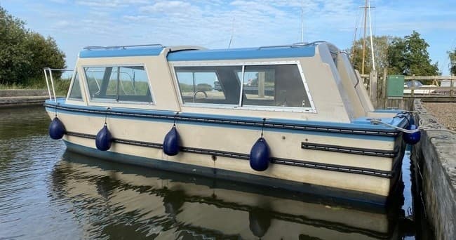 Cream houseboat moored at riverside with fenders visible