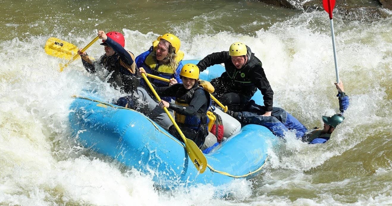 Experienced rafters navigating whitewater rapids in blue raft