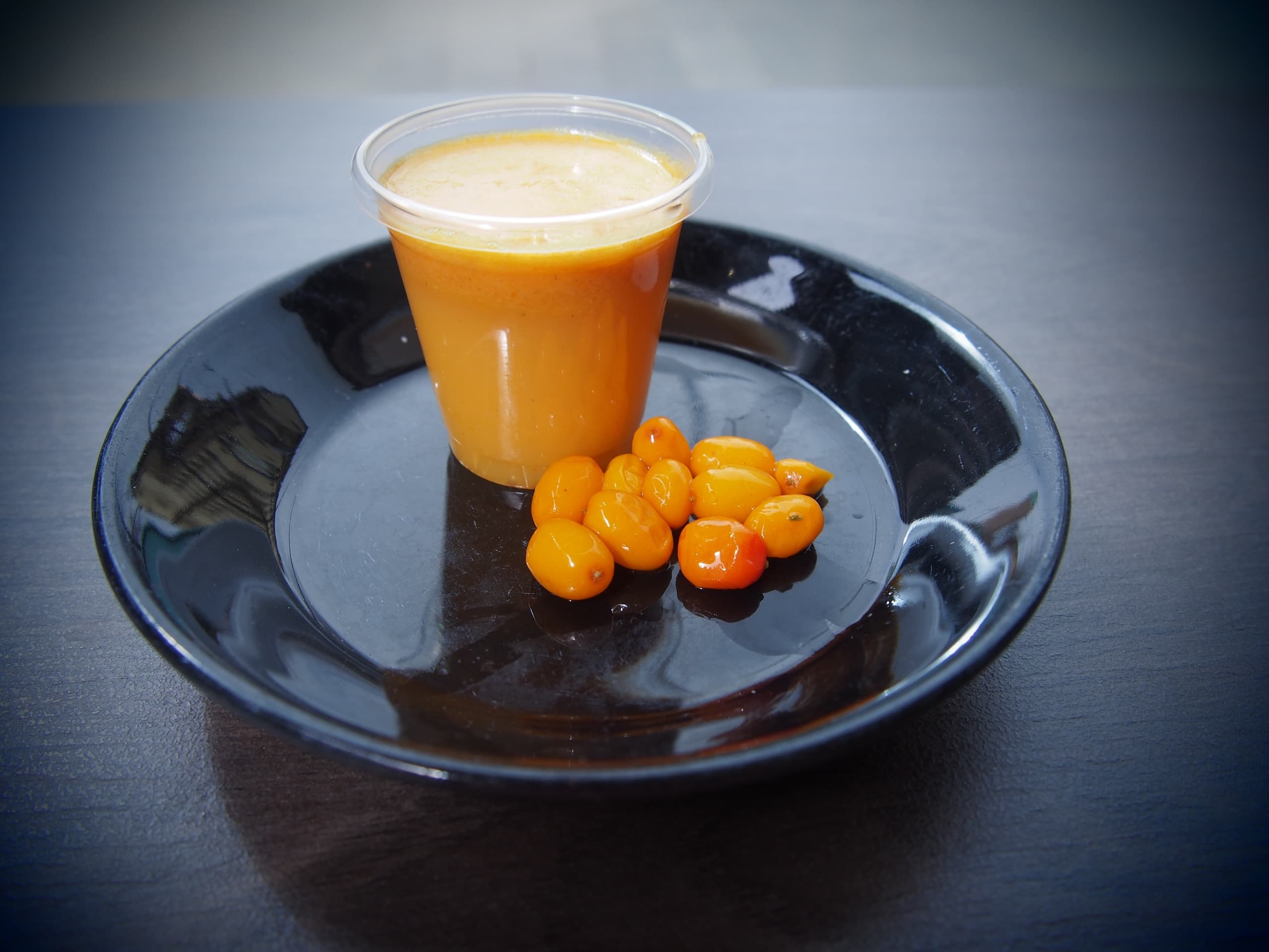 Fresh sea buckthorn juice and berries on plate, minimalist cafe