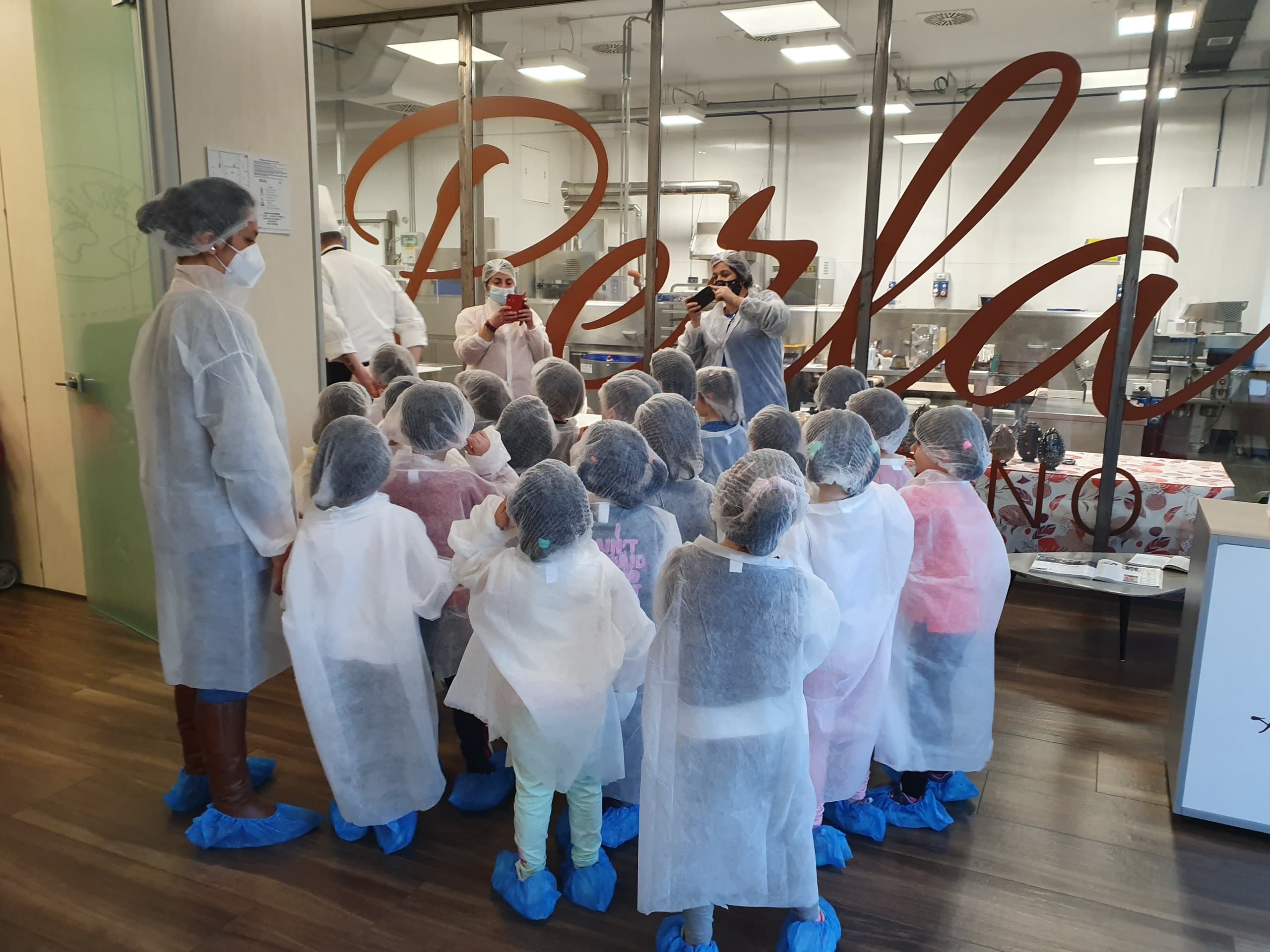 Visitors on guided chocolate factory tour wearing protective gear in Turin