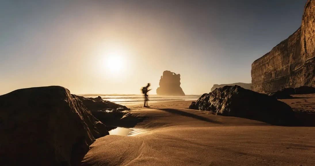 Person running on sunlit coastal rocks at golden sunrise, Australian beach