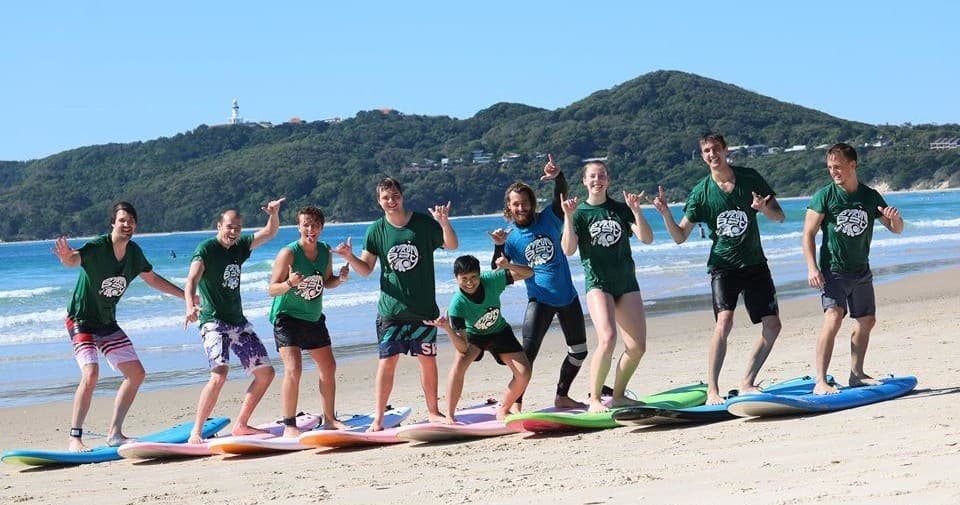 Beginner surfers lined up on Byron Bay beach learning to surf