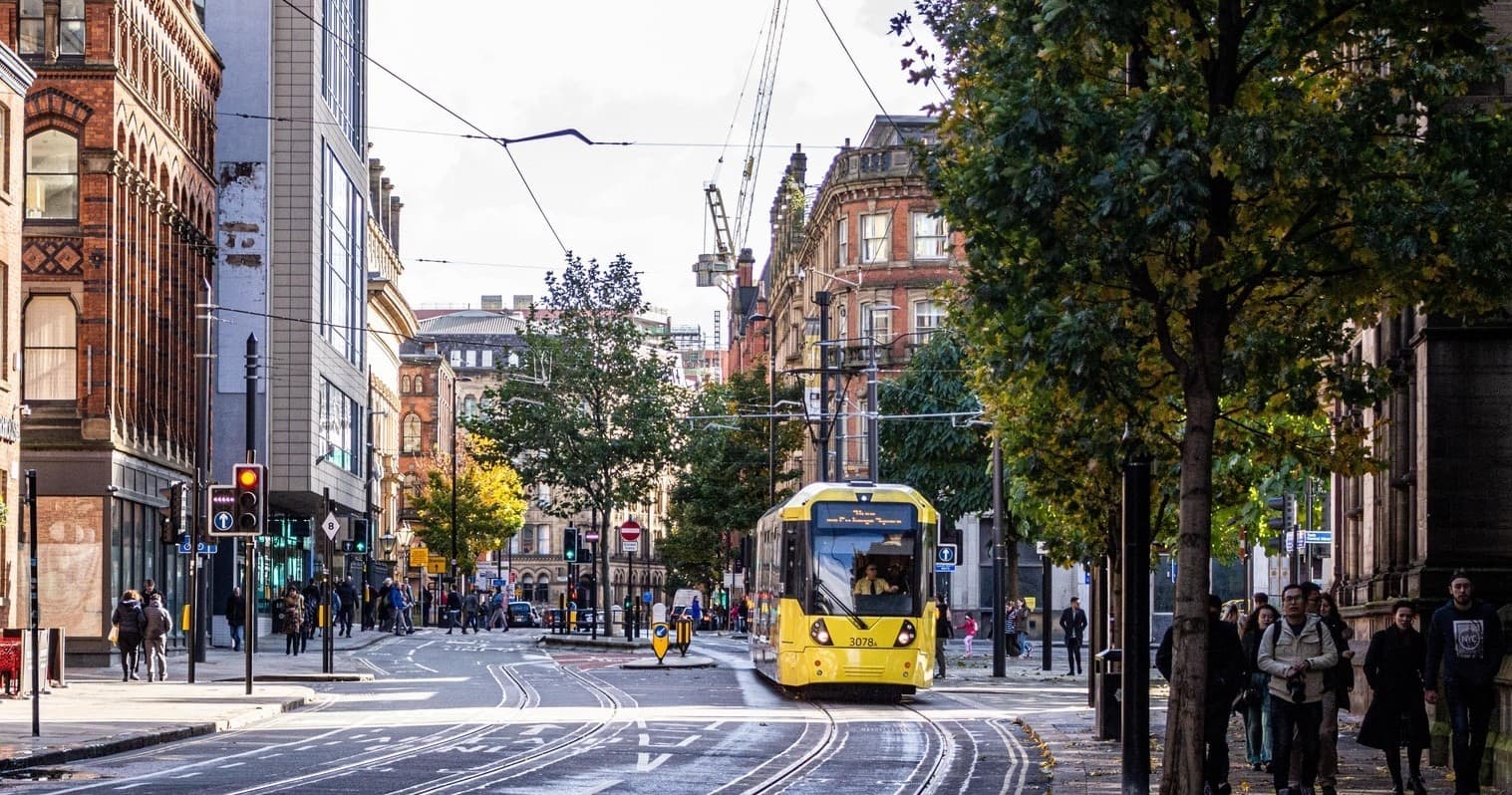 Yellow city tram on busy urban street in UK city walking tour