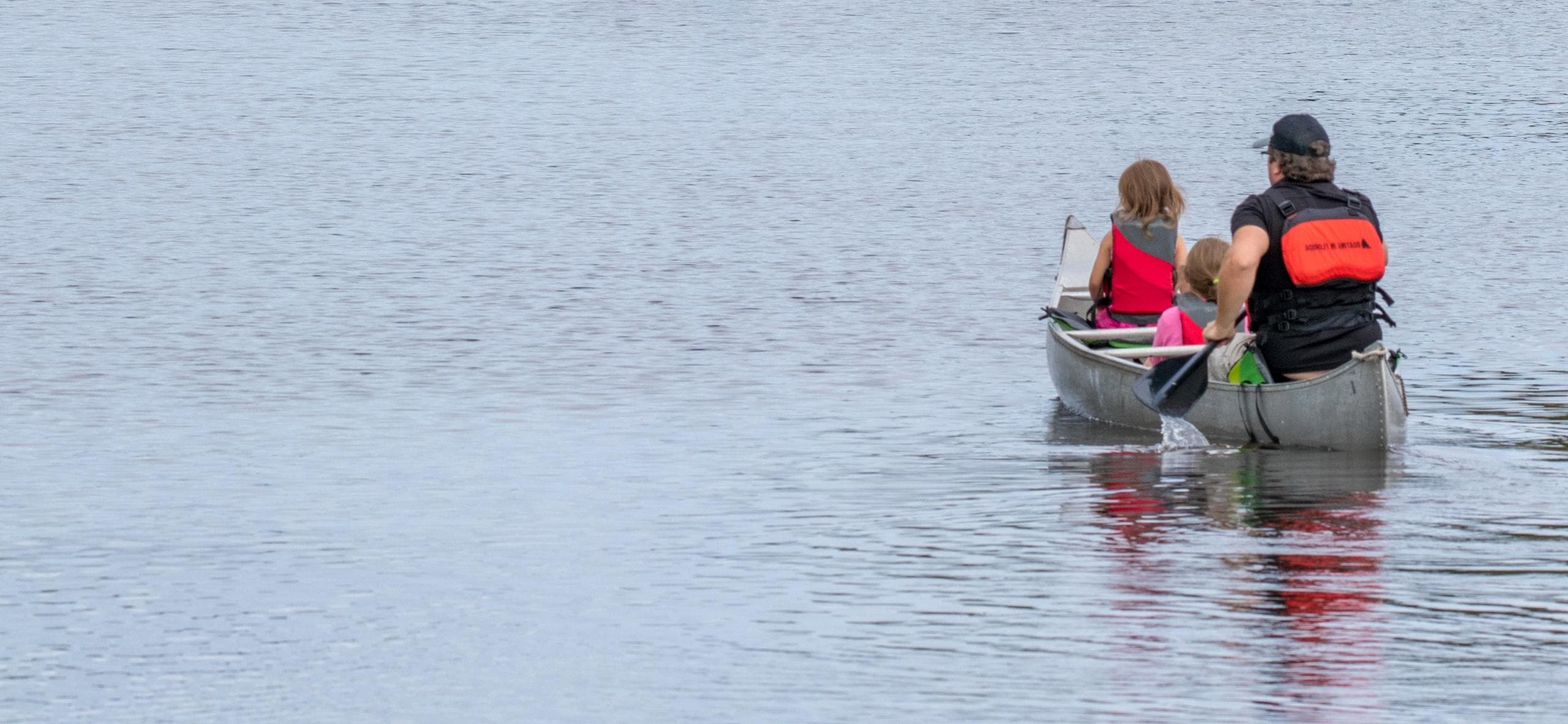 Two-person canoe gliding across open spring river under clear sky